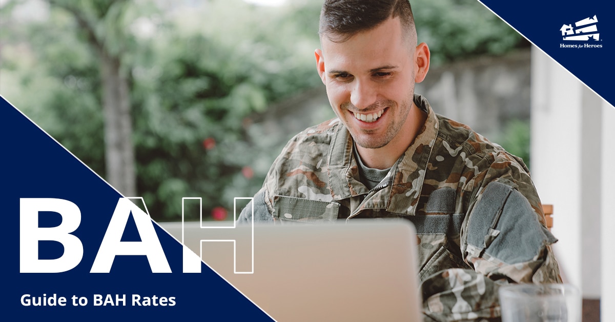 man in military camo smiling while looking at his computer
