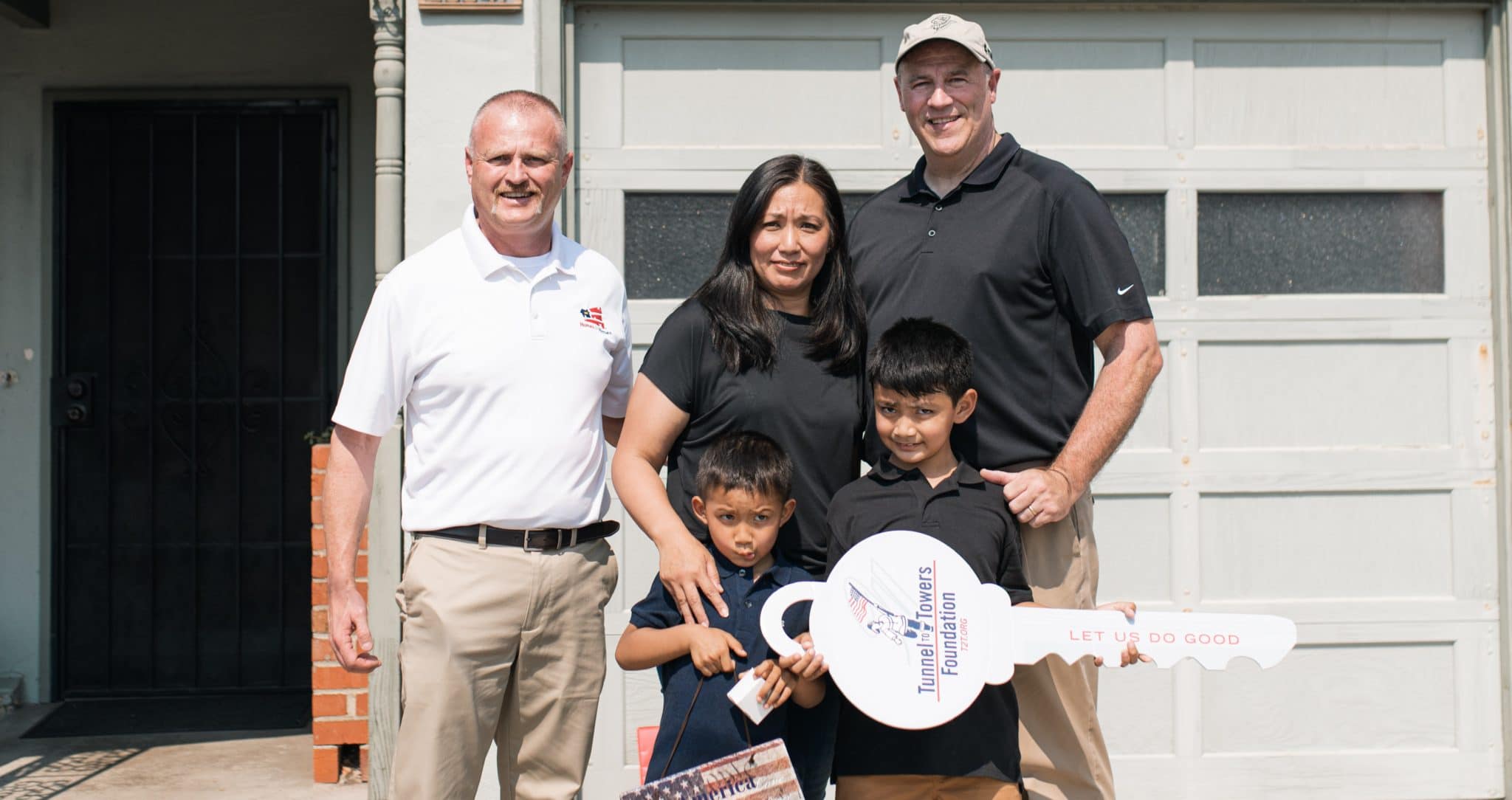 Representatives from Homes for Heroes Foundation and Tunnel to Towers stand with Patricia Cortez and her two sons in front of their San Francisco home