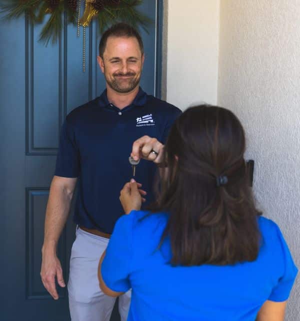 male Homes for Heroes real estate agent handing nurse home buyer keys to new house after closing