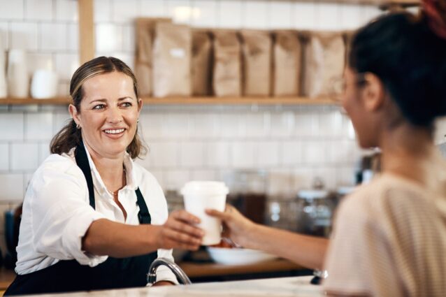 Coffee shop owner serving customer with a warm smile