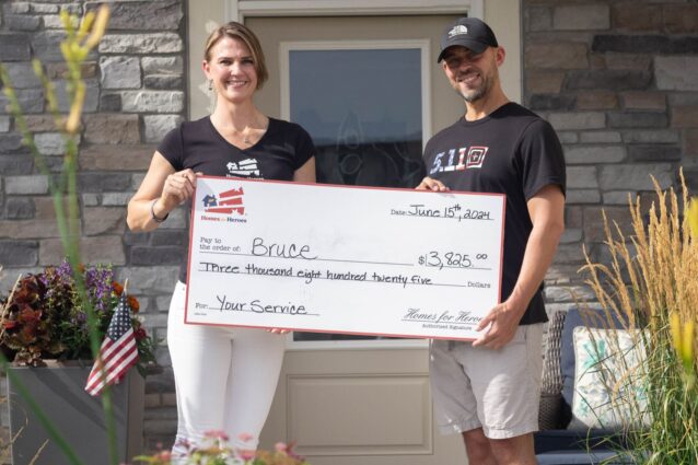 Affiliate specialists holding big check outside hero’s home