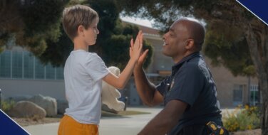 Police Officer high fiving a child with a teddy bear