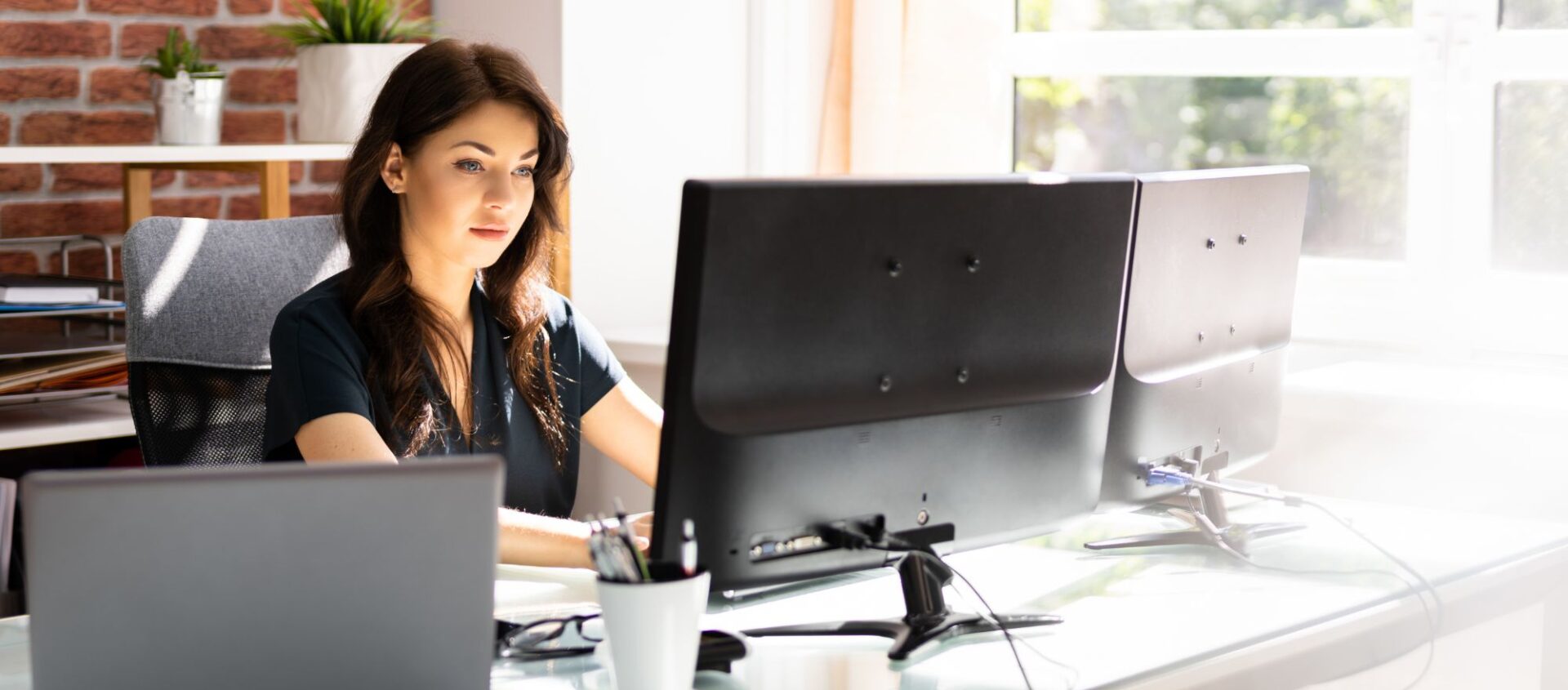 female real estate agent in office sitting at desk working on computer building Facebook ads ppc for real estate