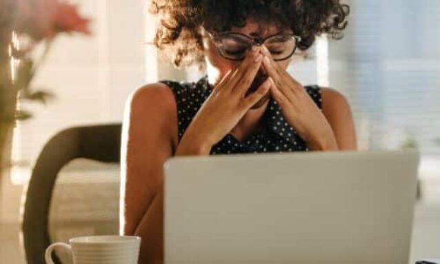 female real estate agent sitting at desk in front of laptop trying to design marketing materials