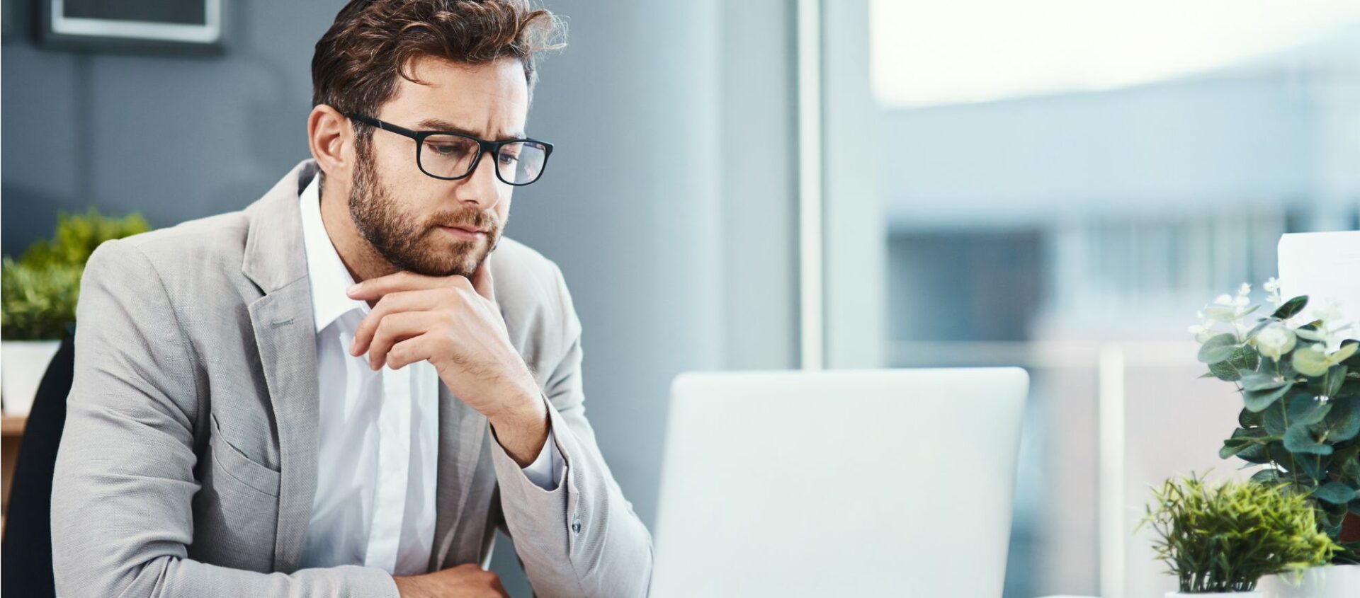 real estate agent working on laptop in office thinking about how to grow his real estate social network with his social media accounts