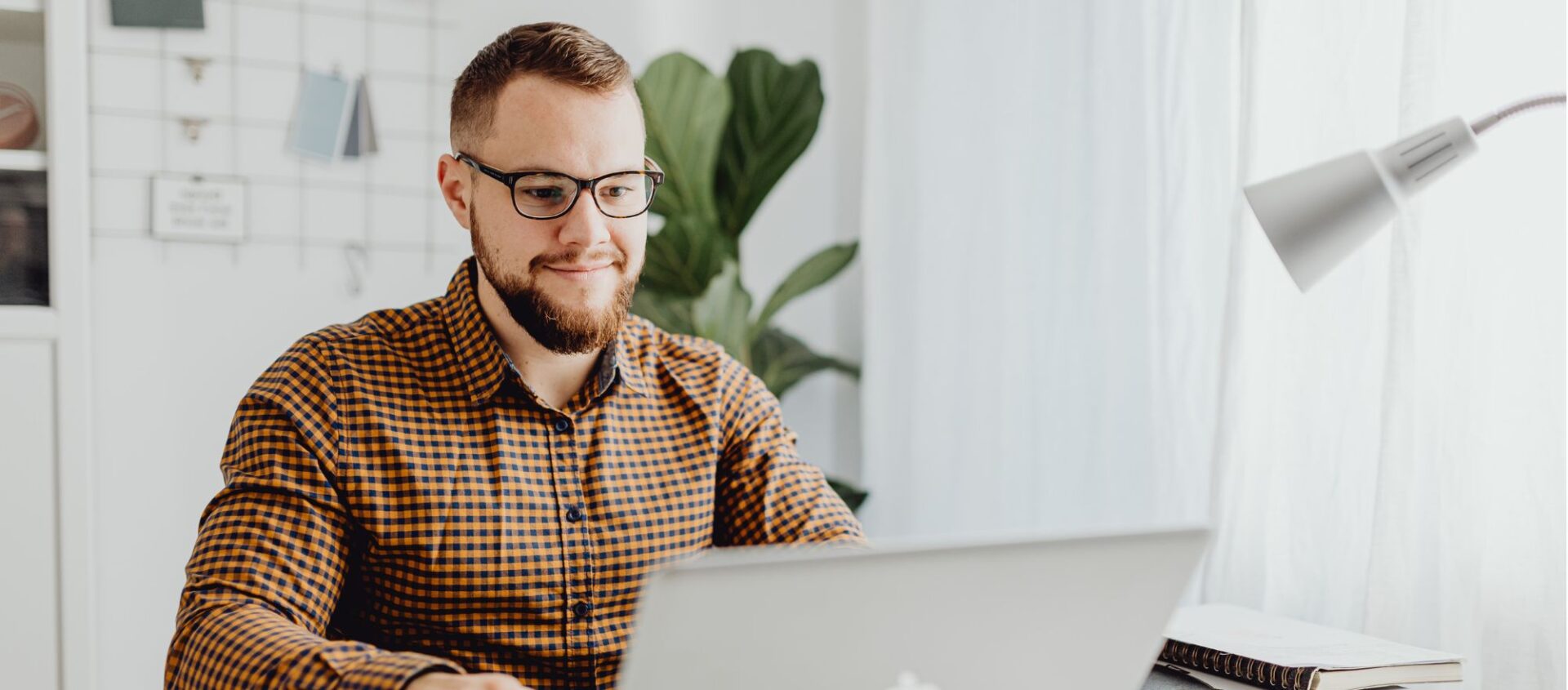 real estate agent sitting at desk in office working on laptop sending follow up real estate marketing emails to clients