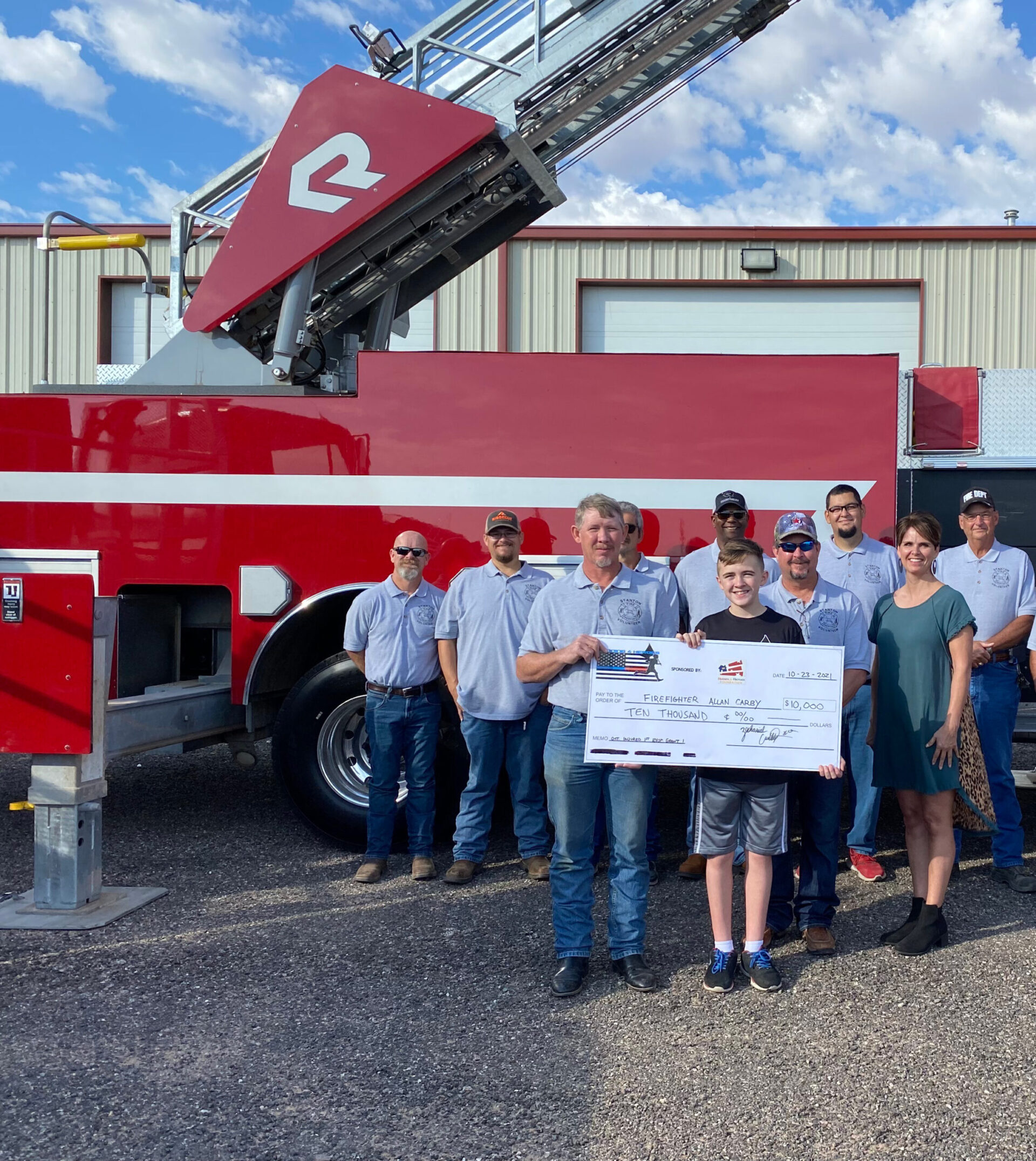 Group posing with Runnin 4 Heroes grant check by fire rig