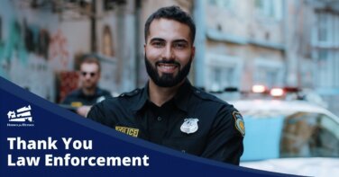 smiling cop in front of police car thank you police officers law enforcement appreciation Homes for Heroes