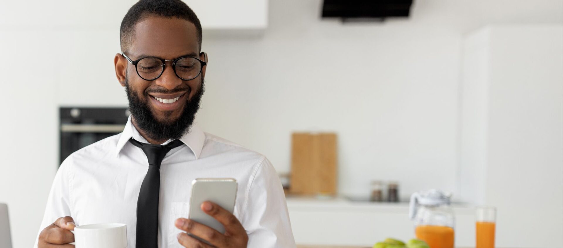 male agent smiling black tie sipping coffee in kitchen managing real estate social media marketing posts before meeting with clients