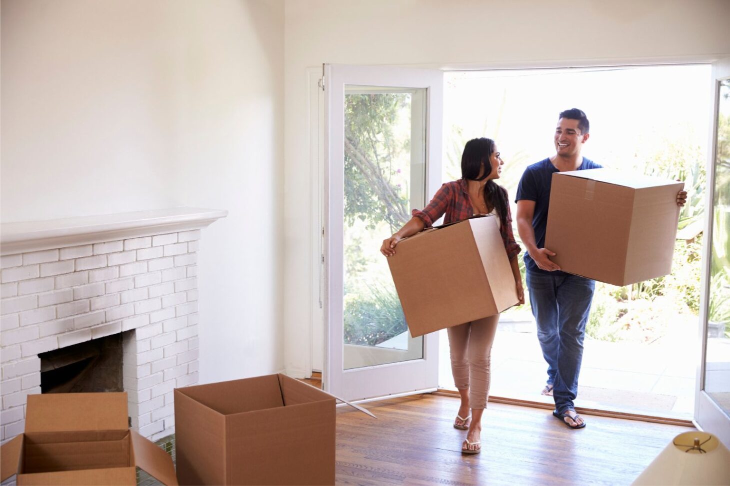 Young couple moving boxes into their newly purchased home