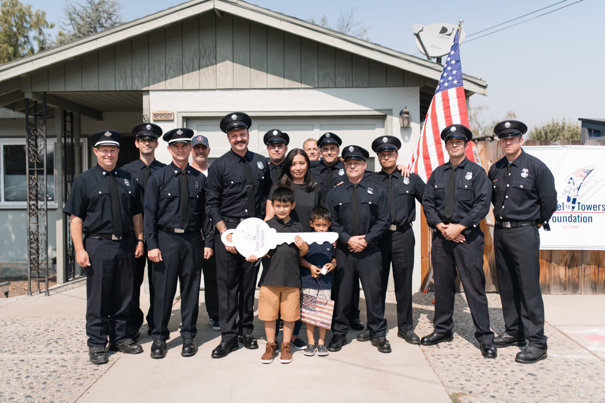 Members of the San Francisco Fire Department stand with Patricia Cortez, Jason Cortez's wife, and their two sons in front of their home.