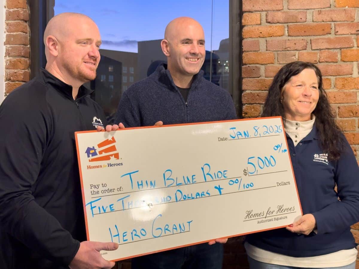 Thin Blue Ride leaders posing with Homes for Heroes Foundation grant big check and real estate specialist during check presentation