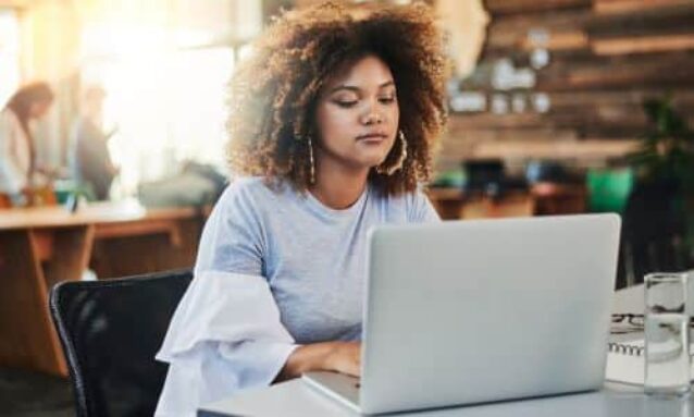 female agent working on real estate marketing plan sitting at table on laptop in coffee shop