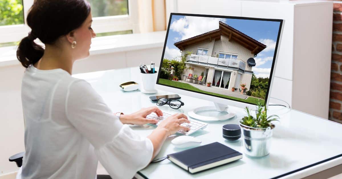 female real estate agent sitting at her desk typing on computer updating listing on website Homes for Heroes